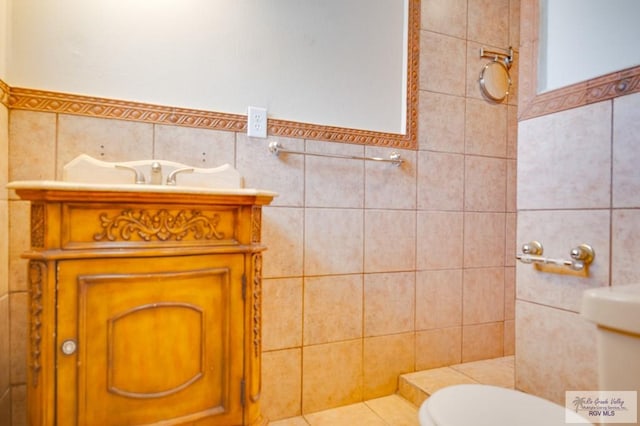 bathroom with vanity, toilet, and tile walls