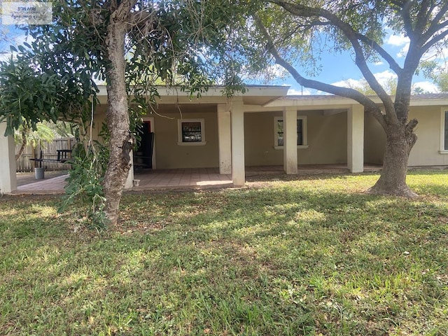 back of property with a lawn and a patio