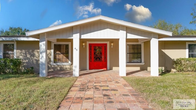 property entrance featuring a lawn and a porch