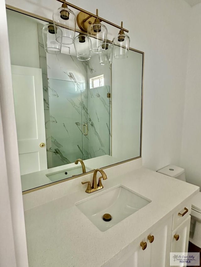 bathroom with a marble finish shower, vanity, and toilet