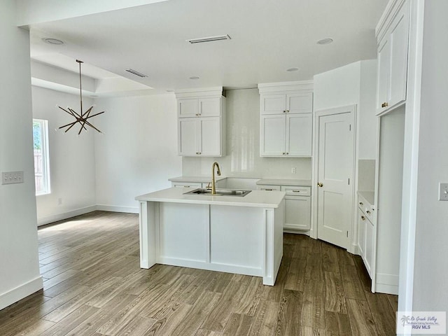 kitchen with visible vents, wood finished floors, a sink, and white cabinetry