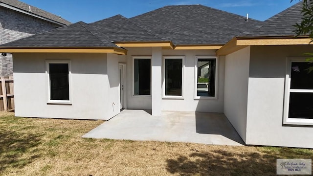 rear view of house featuring a patio area, roof with shingles, a yard, and stucco siding