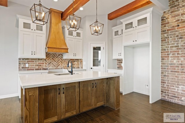 kitchen featuring hanging light fixtures, white cabinets, a kitchen island with sink, and beamed ceiling