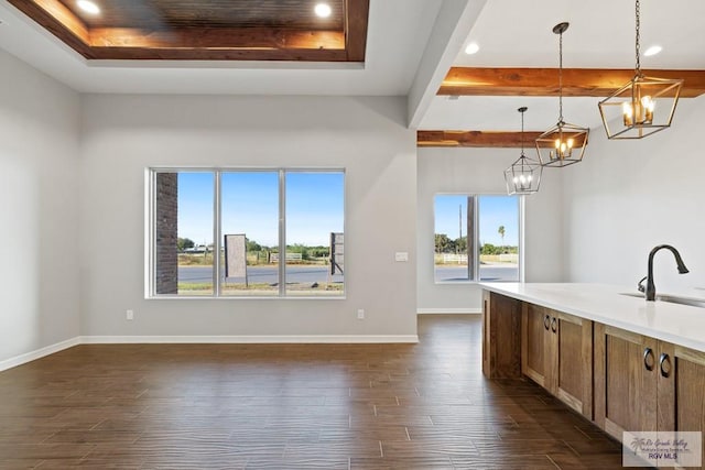 kitchen with a tray ceiling, sink, dark hardwood / wood-style floors, and decorative light fixtures