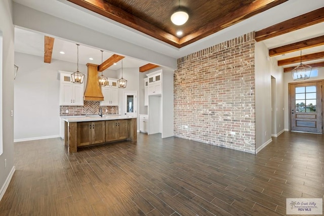 kitchen featuring white cabinets, dark wood-type flooring, hanging light fixtures, and an island with sink