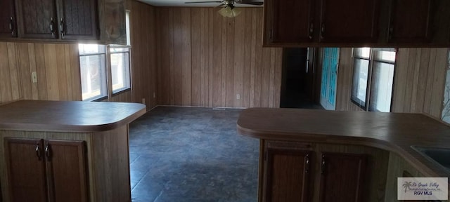 kitchen featuring ceiling fan, wood walls, and kitchen peninsula