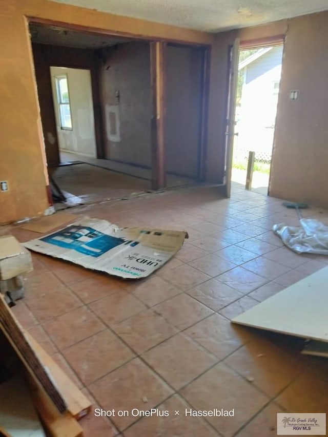 interior space with light tile patterned floors, plenty of natural light, and a textured ceiling