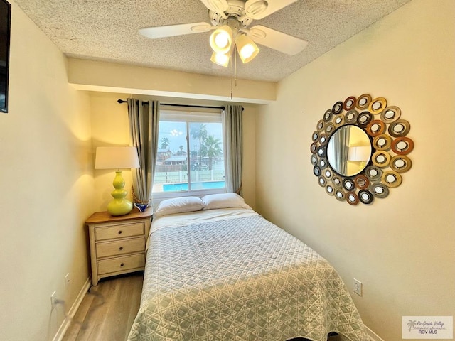 bedroom featuring ceiling fan, hardwood / wood-style floors, and a textured ceiling