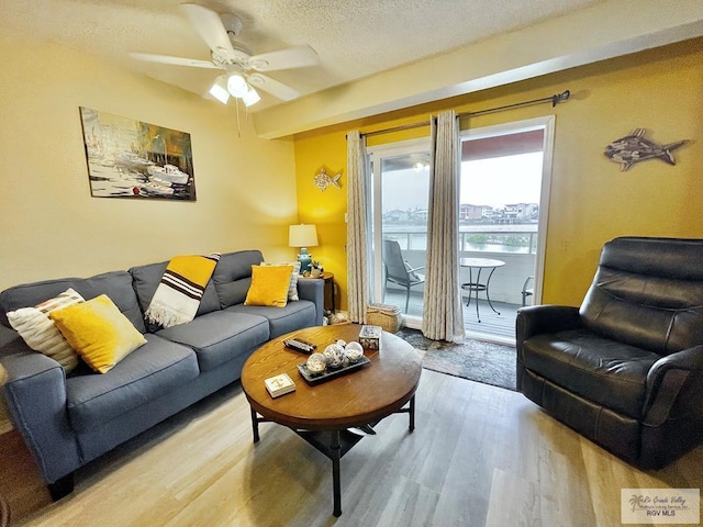 living room featuring ceiling fan, a textured ceiling, and light hardwood / wood-style flooring