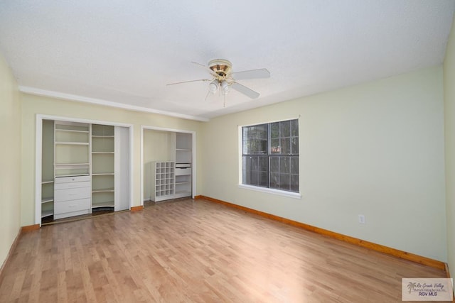 unfurnished bedroom featuring ceiling fan, two closets, light wood-style flooring, and baseboards