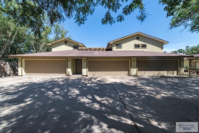 view of front of house with driveway, an attached garage, and stucco siding