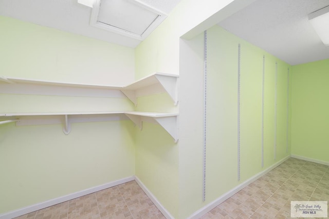 walk in closet with attic access and tile patterned floors