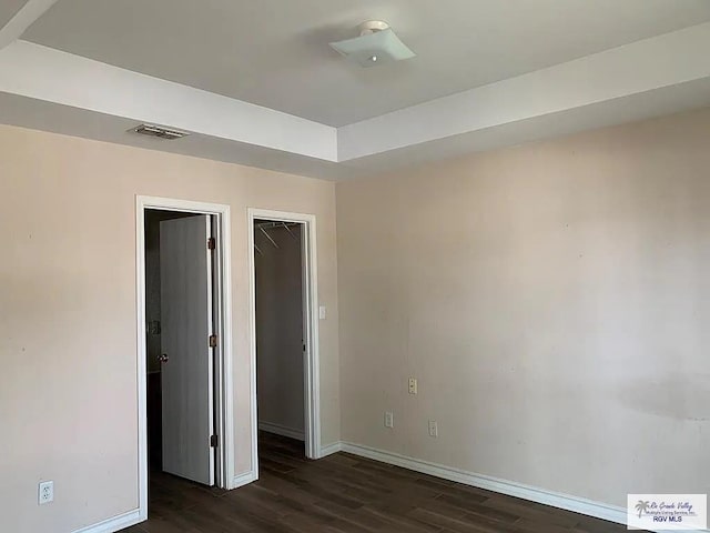 unfurnished bedroom featuring visible vents, baseboards, and dark wood-style flooring