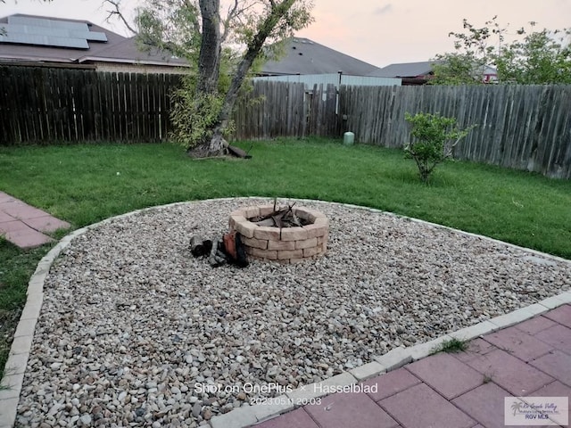 yard at dusk with a fenced backyard and an outdoor fire pit