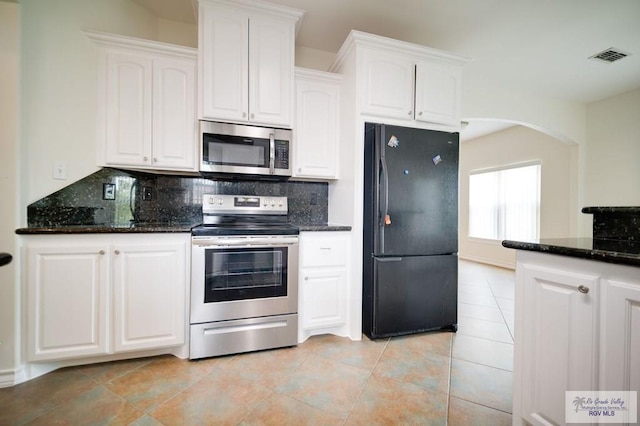 kitchen featuring stainless steel appliances, white cabinetry, tasteful backsplash, and dark stone countertops