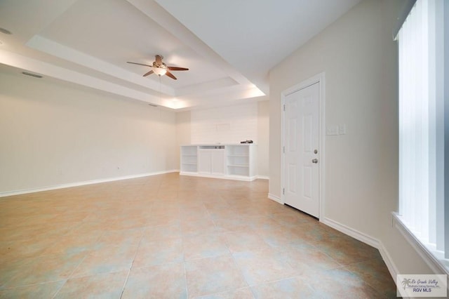 tiled spare room featuring a tray ceiling and ceiling fan