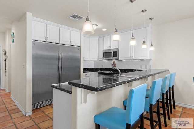 301 Houston Ave Unit 3402, Port Isabel, TX 78578 - kitchen with appliances with stainless steel finishes, decorative backsplash, a peninsula, white cabinets, and pendant lighting