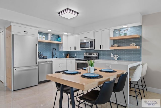 kitchen featuring light tile patterned floors, sink, appliances with stainless steel finishes, white cabinetry, and backsplash