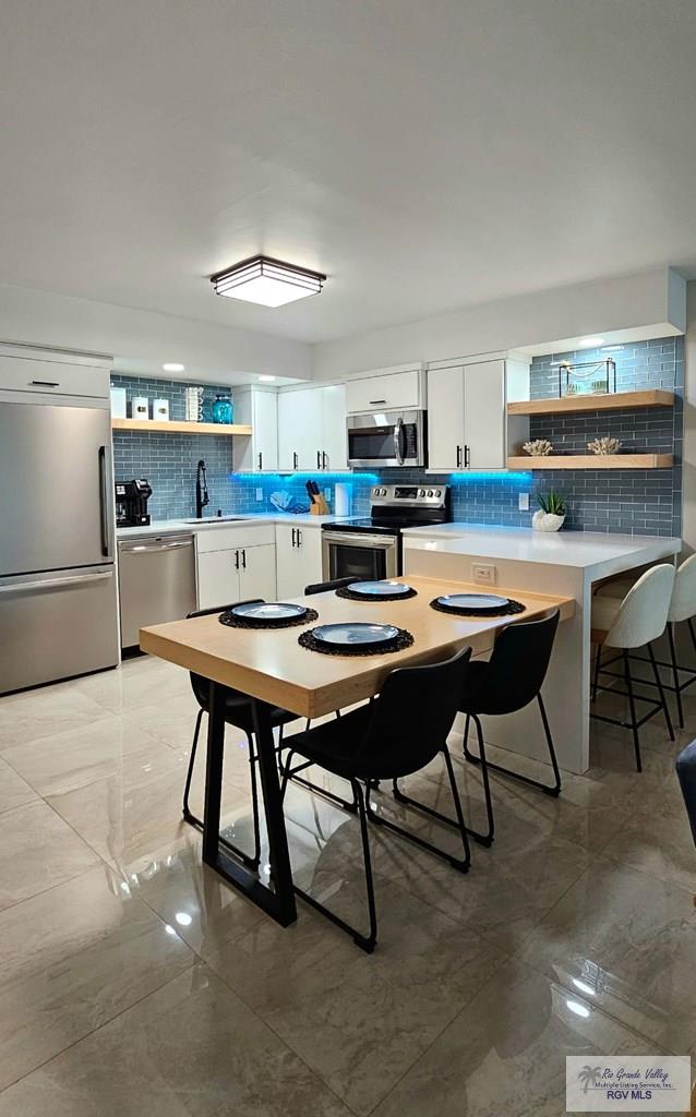 kitchen featuring white cabinetry, sink, decorative backsplash, and stainless steel appliances