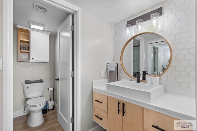 bathroom with vanity, toilet, wood-type flooring, and backsplash