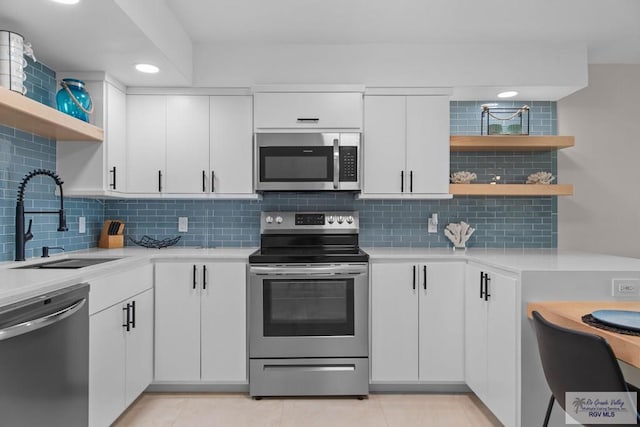 kitchen with sink, backsplash, stainless steel appliances, and white cabinets