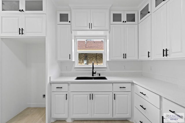 kitchen with white cabinetry, light hardwood / wood-style floors, and sink