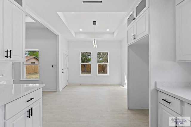 kitchen with white cabinetry, a raised ceiling, light hardwood / wood-style floors, and a wealth of natural light