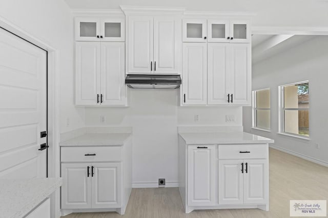 kitchen featuring white cabinetry, light wood-type flooring, and light stone counters