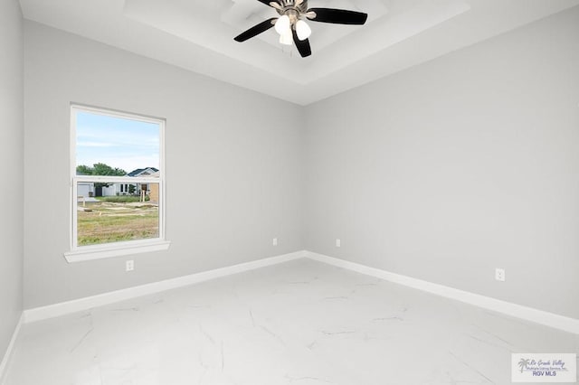 spare room with a tray ceiling and ceiling fan