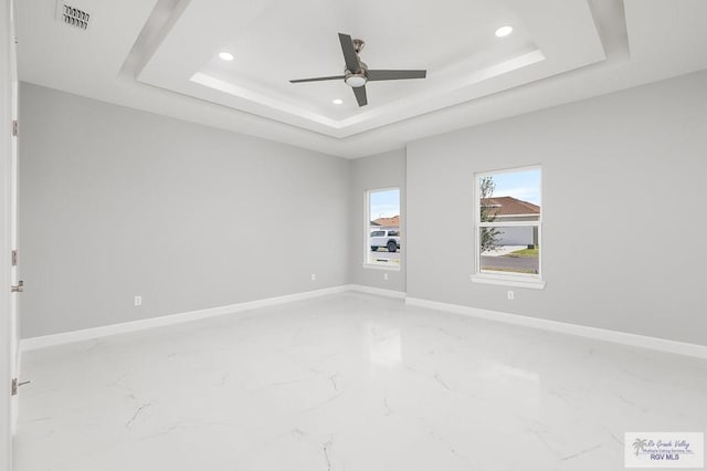 unfurnished room with ceiling fan and a raised ceiling