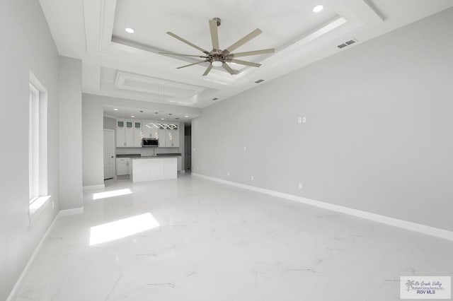 unfurnished living room with a raised ceiling and ceiling fan