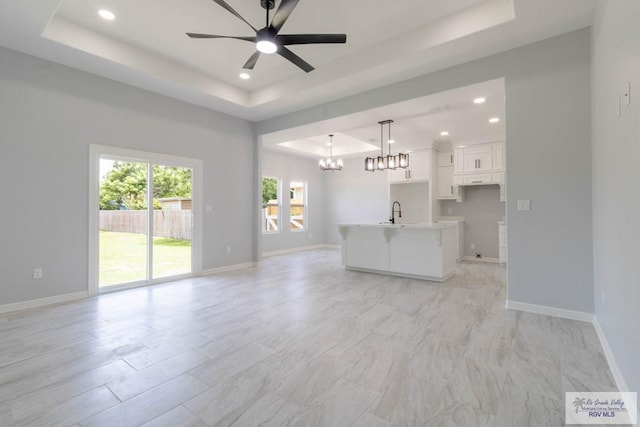 21929 Hand Rd, Harlingen, TX 78552 - unfurnished living room with a raised ceiling, a chandelier, recessed lighting, baseboards, and a sink