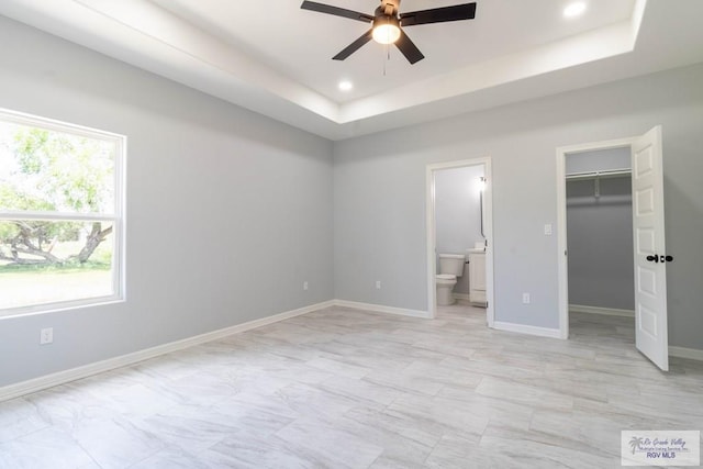 21929 Hand Rd, Harlingen, TX 78552 - unfurnished bedroom featuring a walk in closet, ensuite bathroom, a tray ceiling, recessed lighting, and baseboards