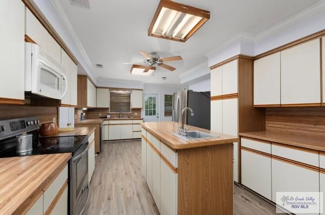 501 Ratliff St, San Benito, TX 78586 - kitchen featuring appliances with stainless steel finishes, wooden counters, decorative backsplash, light wood-style flooring, and crown molding