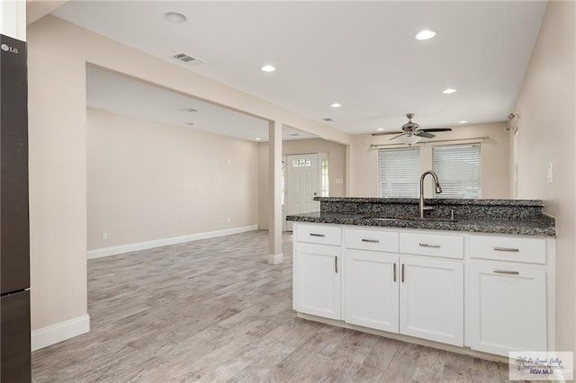 kitchen featuring sink, white cabinets, dark stone counters, and light wood-type flooring