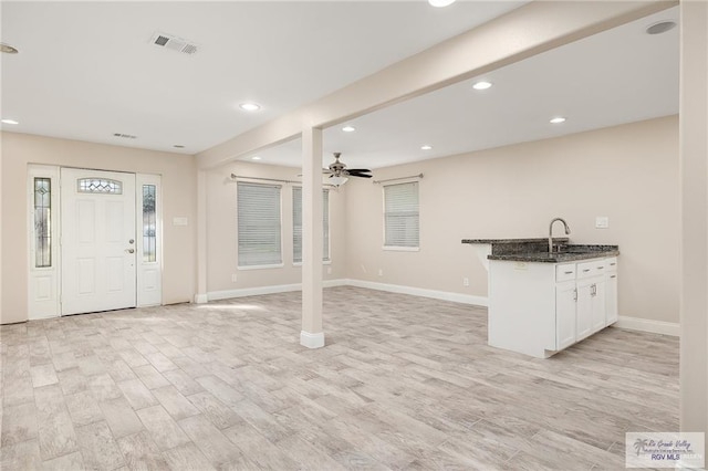 interior space featuring light hardwood / wood-style floors, white cabinetry, ceiling fan, and dark stone countertops