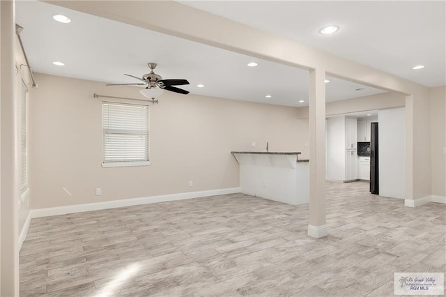 unfurnished living room featuring ceiling fan and light hardwood / wood-style flooring