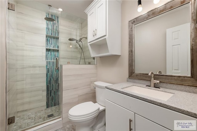 bathroom with vanity, toilet, walk in shower, and tile walls