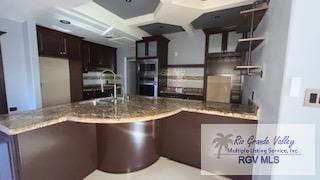 kitchen featuring double oven, kitchen peninsula, sink, and dark brown cabinets