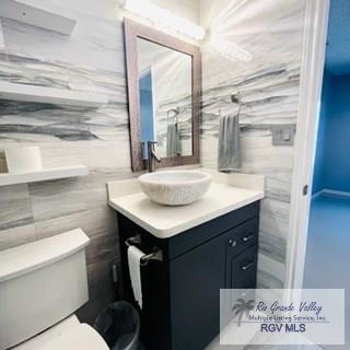 bathroom with vanity, tile walls, and toilet