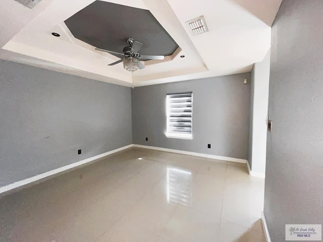 unfurnished room featuring a tray ceiling, ceiling fan, and tile patterned floors