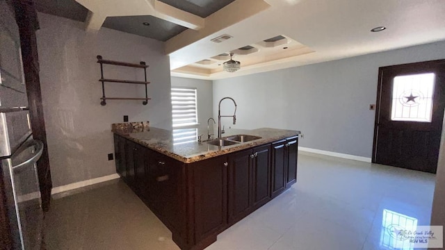 kitchen featuring light stone countertops, sink, and a tray ceiling