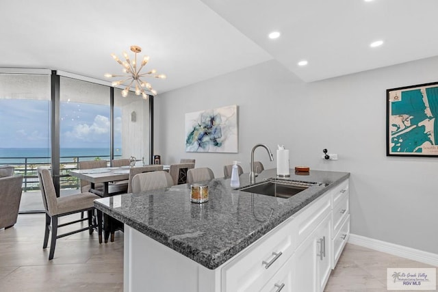 kitchen featuring dark stone counters, a water view, sink, white cabinetry, and kitchen peninsula