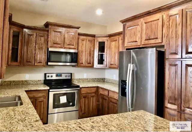 401 S Tamm Ln, Harlingen, TX 78550 - kitchen featuring appliances with stainless steel finishes, light stone countertops, glass insert cabinets, and recessed lighting