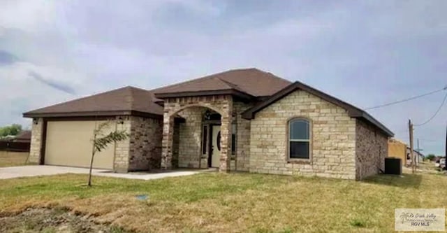 401 S Tamm Ln, Harlingen, TX 78550 - view of front of house featuring a garage, driveway, a front yard, and stone siding