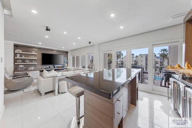 kitchen featuring light tile patterned flooring, built in shelves, french doors, a center island, and dark stone countertops