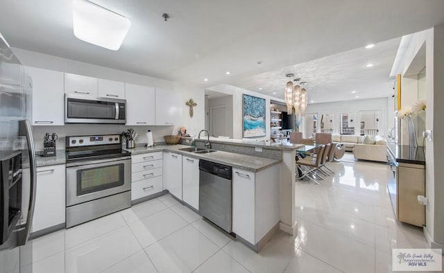 kitchen featuring appliances with stainless steel finishes, sink, white cabinets, light tile patterned floors, and kitchen peninsula