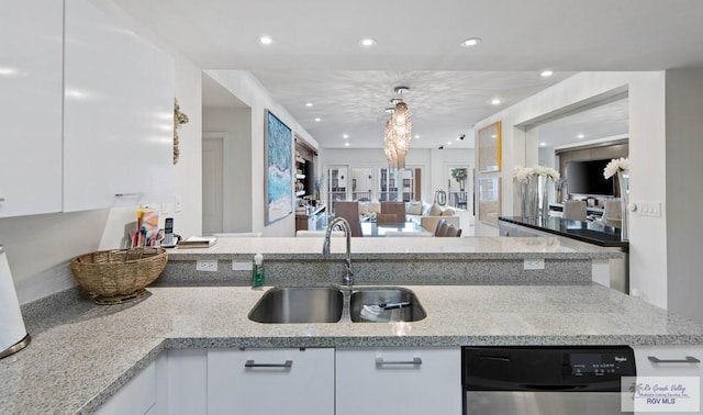 kitchen with sink, white cabinets, light stone counters, and decorative light fixtures