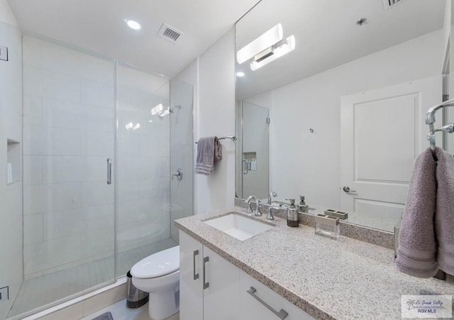 bathroom featuring vanity, a shower with shower door, and toilet