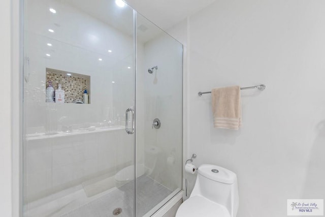 bathroom featuring toilet and a shower with shower door